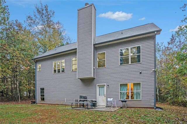 back of property with a lawn and a patio