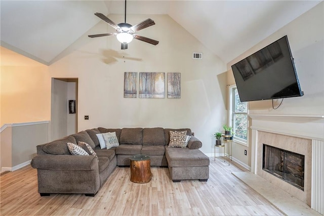 living room featuring a premium fireplace, ceiling fan, and light hardwood / wood-style floors