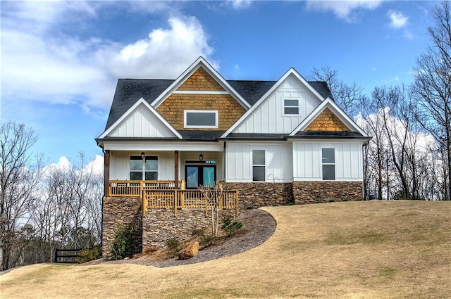 craftsman inspired home with board and batten siding, a porch, a front yard, roof with shingles, and french doors