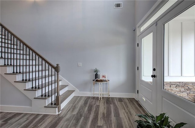 foyer entrance with visible vents, stairs, baseboards, and wood finished floors