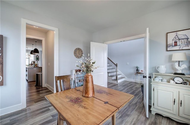 dining room with stairs, baseboards, and wood finished floors