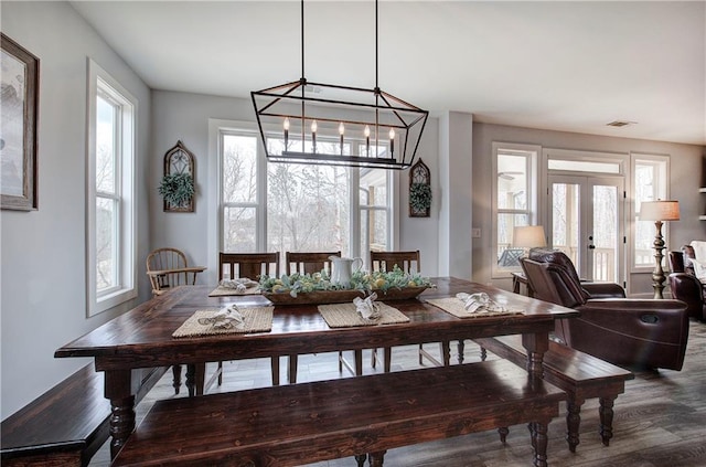 dining space with french doors, an inviting chandelier, wood finished floors, and visible vents