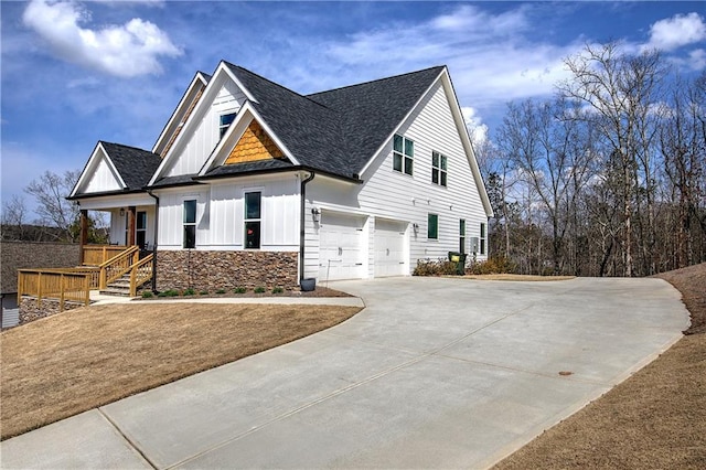 view of front of property featuring board and batten siding, a shingled roof, concrete driveway, stone siding, and an attached garage