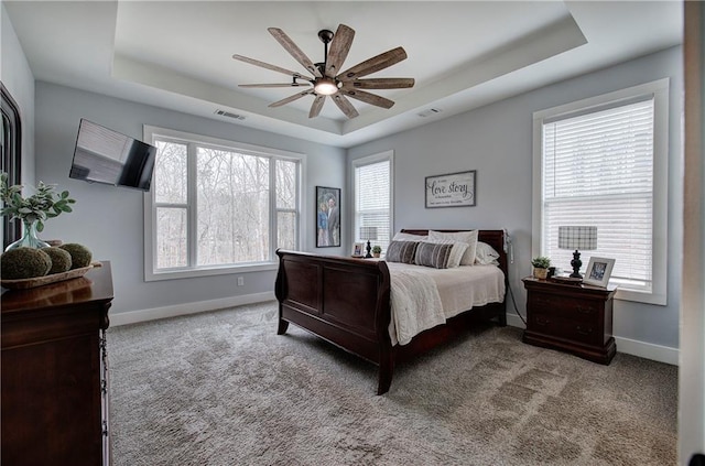 carpeted bedroom with a raised ceiling, baseboards, and visible vents