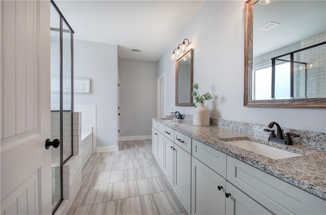 full bath featuring a bath, visible vents, double vanity, and a sink