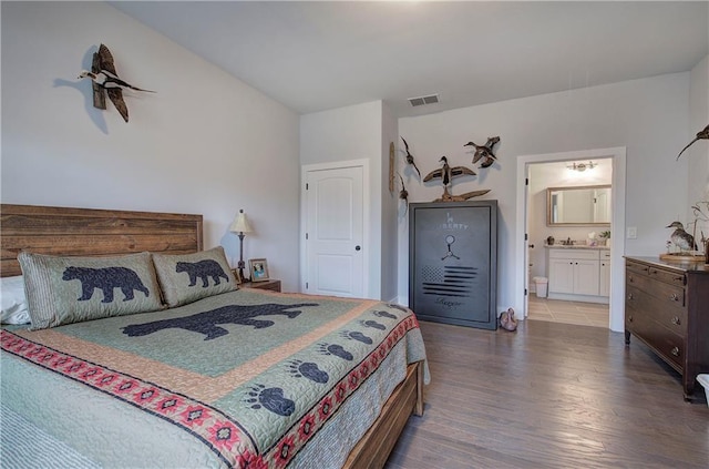 bedroom with ensuite bath, wood finished floors, and visible vents