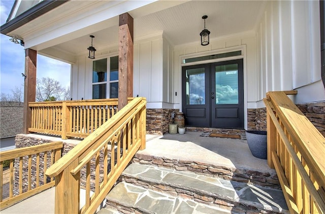 entrance to property featuring a porch, french doors, board and batten siding, and stone siding