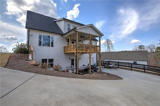 exterior space with driveway, roof with shingles, a ceiling fan, and fence