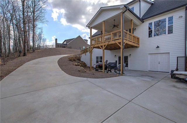 back of property featuring a shingled roof, fence, concrete driveway, a ceiling fan, and a patio