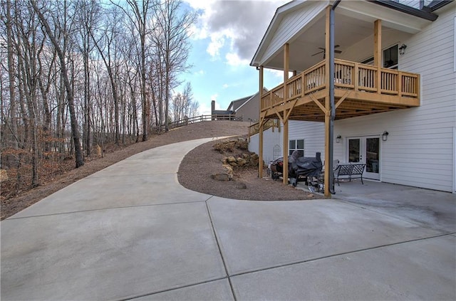 view of patio / terrace featuring a deck, french doors, driveway, and a ceiling fan