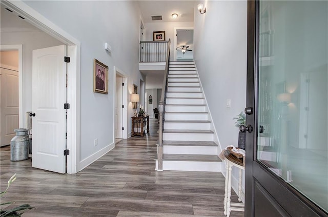 entrance foyer featuring wood finished floors, visible vents, baseboards, a high ceiling, and stairs