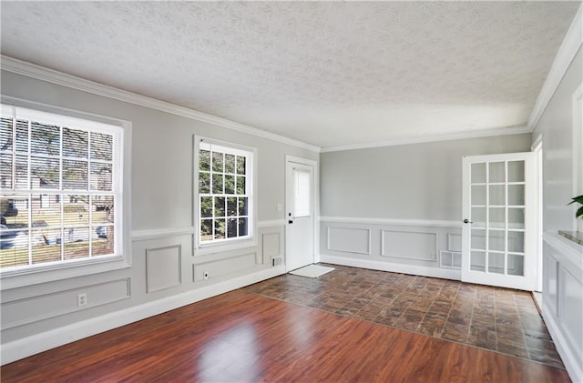 spare room featuring dark hardwood / wood-style flooring, crown molding, and a healthy amount of sunlight