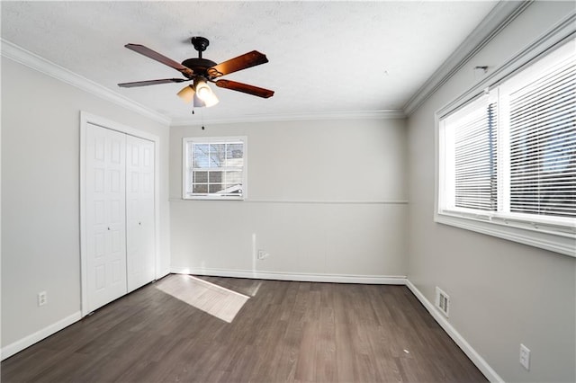 unfurnished bedroom with ceiling fan, dark wood-type flooring, ornamental molding, and a closet