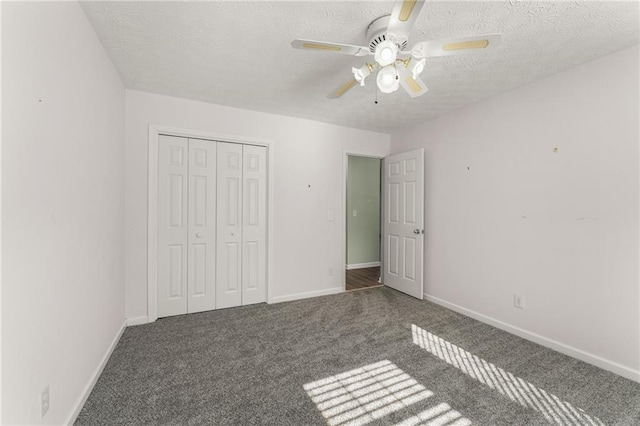 unfurnished bedroom featuring ceiling fan, dark carpet, a closet, and a textured ceiling