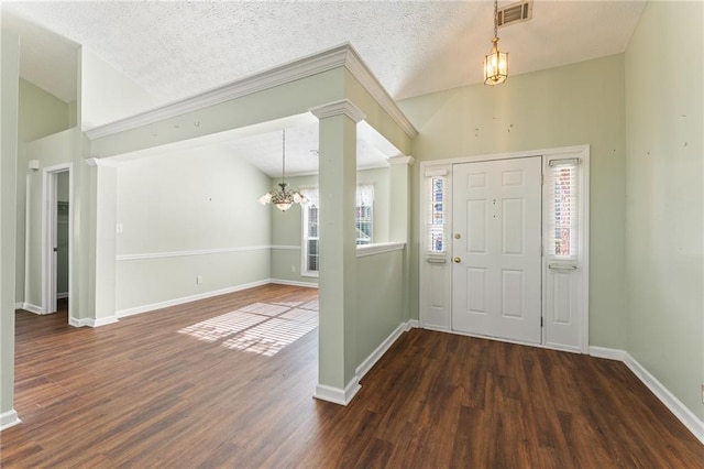 foyer with lofted ceiling, ornate columns, an inviting chandelier, a textured ceiling, and dark hardwood / wood-style flooring