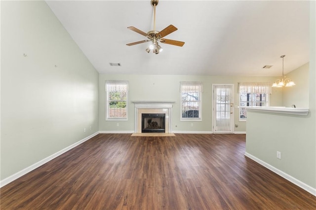 unfurnished living room with ceiling fan with notable chandelier, dark hardwood / wood-style floors, and vaulted ceiling