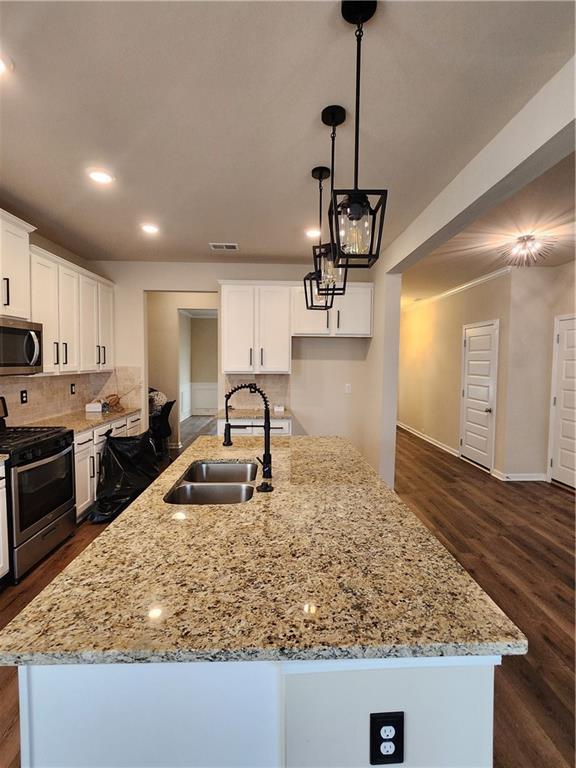 kitchen featuring white cabinetry, appliances with stainless steel finishes, sink, and a center island with sink