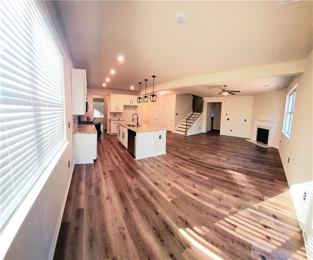 unfurnished living room with ceiling fan, dark hardwood / wood-style flooring, and sink