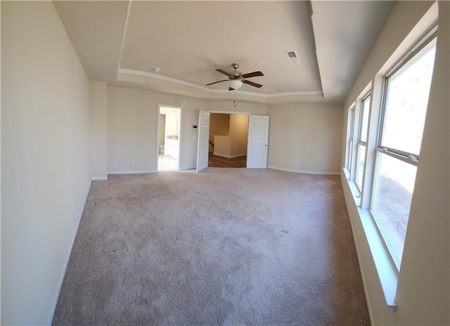 carpeted spare room featuring a raised ceiling and ceiling fan