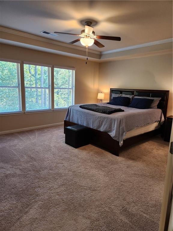 bedroom featuring ornamental molding, a raised ceiling, ceiling fan, and carpet flooring