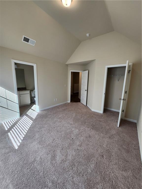 unfurnished bedroom with vaulted ceiling, carpet flooring, and a closet