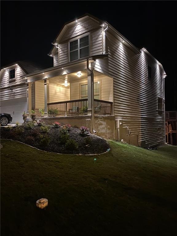 view of front of house with a garage, covered porch, and a lawn