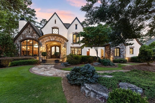 view of front of property with french doors and a lawn