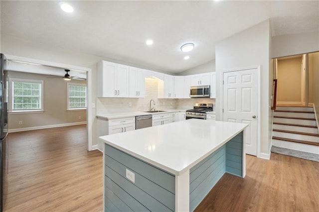 kitchen with white cabinets, stainless steel appliances, lofted ceiling, and light wood-type flooring