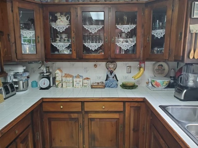 kitchen featuring sink, tile counters, and backsplash