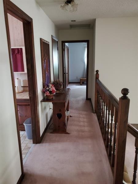 hallway with light colored carpet and a textured ceiling