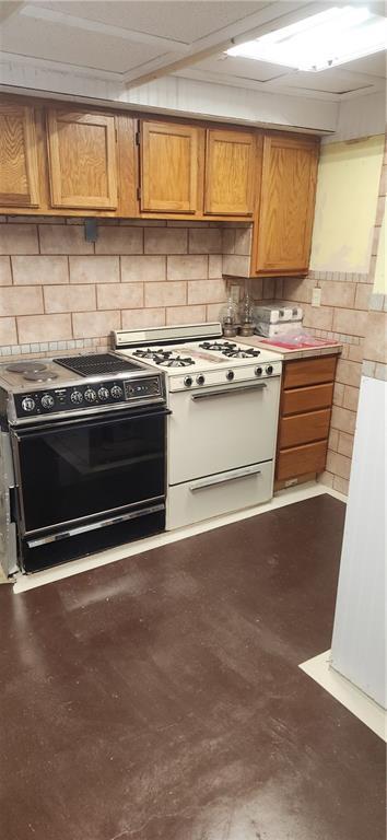 kitchen with white range with gas cooktop, decorative backsplash, and black range with electric cooktop