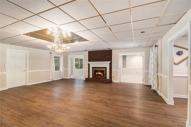 402 Clyde Ct, Mcdonough, GA 30252 - unfurnished living room featuring wood finished floors, a paneled ceiling, a brick fireplace, and a chandelier