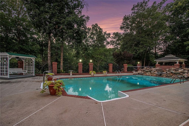 402 Clyde Ct, Mcdonough, GA 30252 - pool at dusk featuring a gazebo, a patio, and view of wooded area
