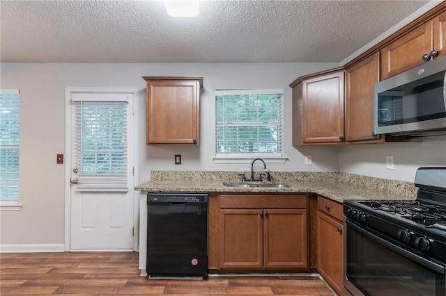 6304 Kendra Ln, Lithonia, GA 30058 - kitchen featuring black appliances, a textured ceiling, dark wood-type flooring, light stone counters, and brown cabinets