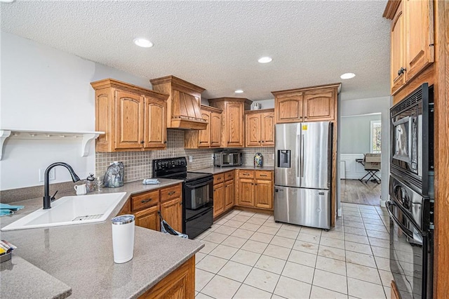 kitchen with tasteful backsplash, light tile patterned floors, a sink, black appliances, and brown cabinetry