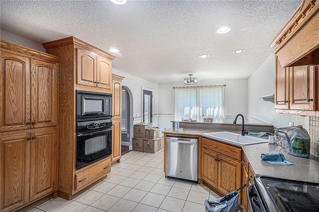 kitchen with light tile patterned floors, a sink, a peninsula, black appliances, and brown cabinets