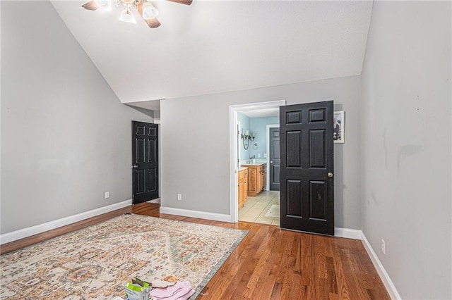 entrance foyer featuring a ceiling fan, light wood-style flooring, baseboards, and lofted ceiling