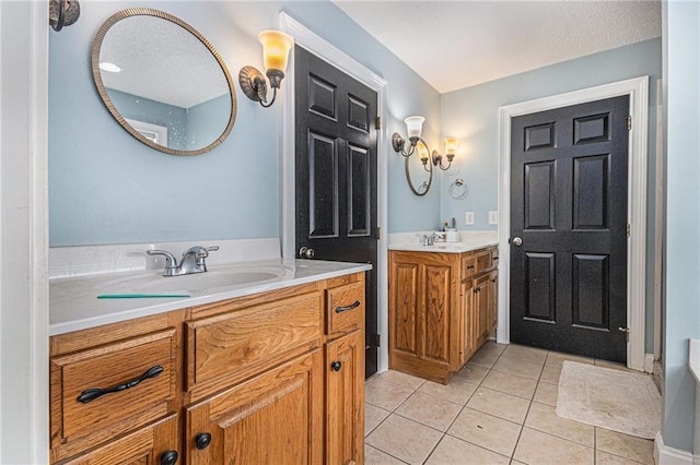 full bathroom featuring tile patterned floors, a textured ceiling, a sink, and two vanities