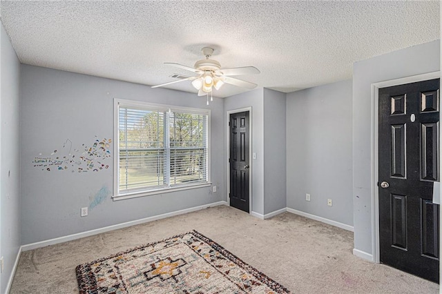 carpeted bedroom with a ceiling fan, visible vents, baseboards, and a textured ceiling
