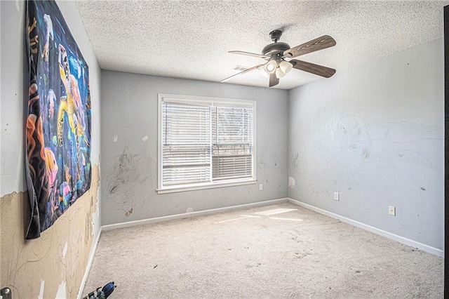 spare room with a textured ceiling, carpet floors, baseboards, and a ceiling fan