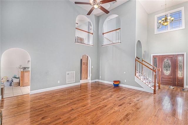 entryway with arched walkways, baseboards, visible vents, and wood-type flooring