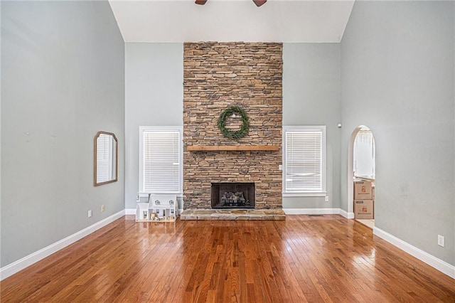 unfurnished living room with baseboards, a fireplace, hardwood / wood-style flooring, and a ceiling fan