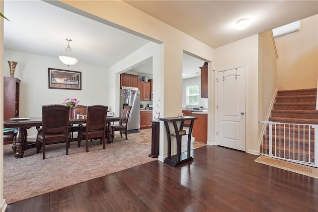 dining area featuring dark wood-style floors, baseboards, and stairway