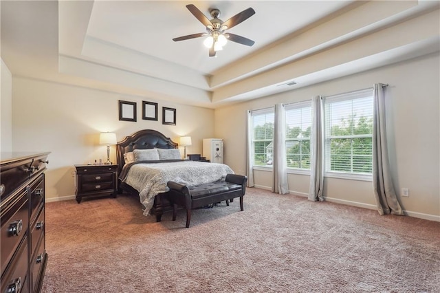 bedroom with a raised ceiling, light colored carpet, and baseboards