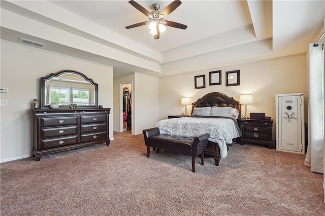 bedroom featuring carpet, visible vents, a walk in closet, and a tray ceiling