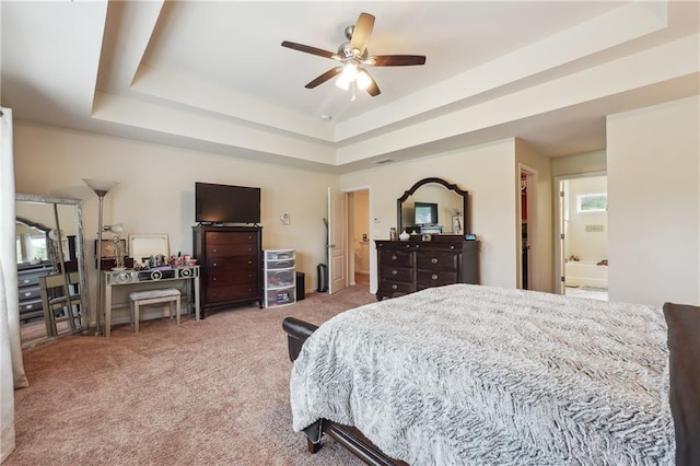 carpeted bedroom with a tray ceiling and connected bathroom