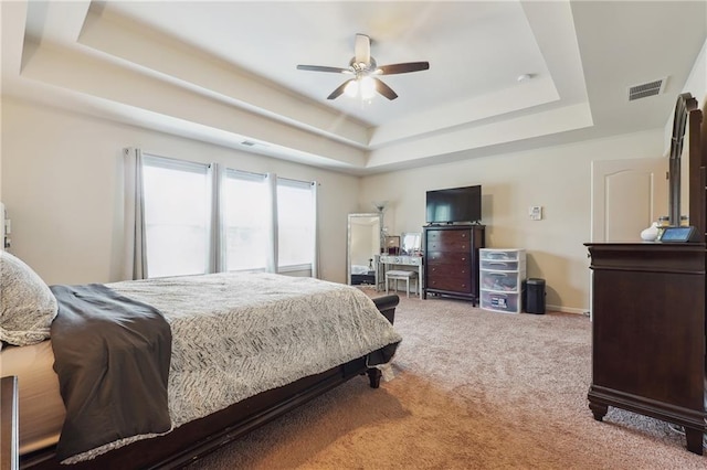 bedroom with carpet flooring, visible vents, baseboards, a ceiling fan, and a raised ceiling