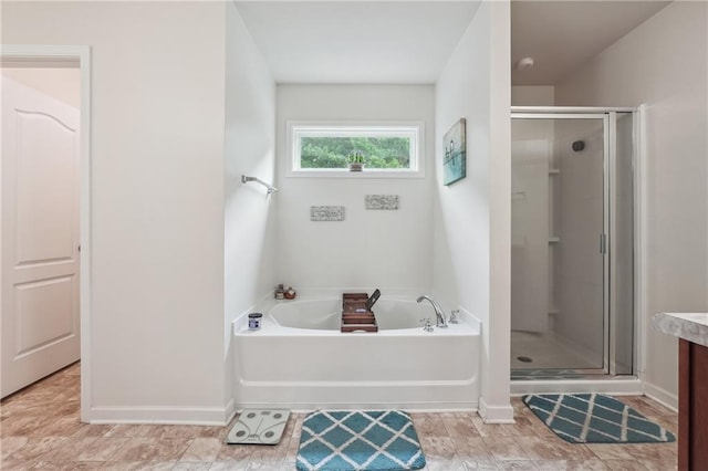 full bathroom with a garden tub, a shower stall, baseboards, and vanity