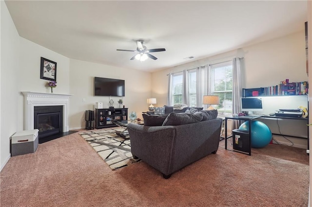 living room with a fireplace with flush hearth, carpet flooring, baseboards, and a ceiling fan