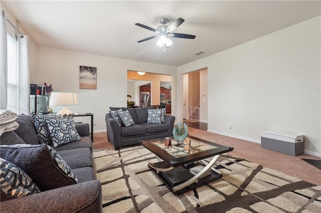 living area with visible vents, stairway, light carpet, ceiling fan, and baseboards